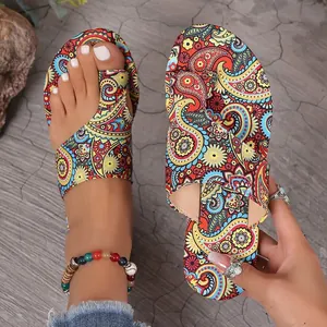 Detailed macro view of women's ethnic paisley print flat toe-loop slippers worn on model