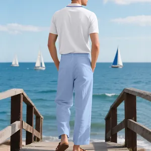 Rückansicht eines Mannes in weißem Polo und blauen Leinenhosen auf einem Steg am Meer.
