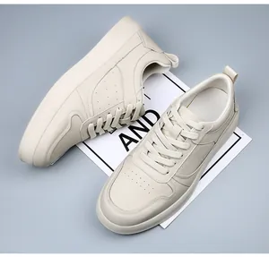 Vue de dessus de baskets en cuir crème avec des détails perforés sur fond gris.