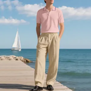 Herren Polo-Shirt in Rosa und beige Leinenhose Set, getragen von einem Model am Meer.