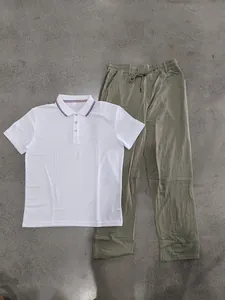 Detailaufnahme eines weißen Poloshirts und einer olivgrünen Leinenhose auf grauem Boden