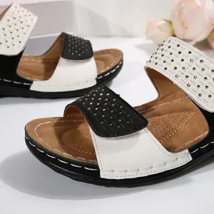 Detailansicht der Damen-Plateausandalen in Schwarz und Weiß mit funkelnden Strassriemen