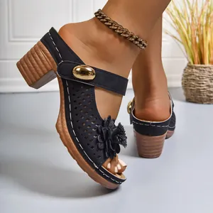Detailed macro view of black laser-cut mule sandals featuring floral decor and chunky heel