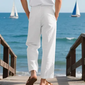 Back view of men's loose white linen trousers walking along a sunny wooden beach pier