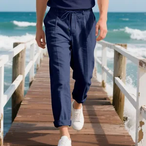 Detailed view of navy blue linen trousers worn by a man walking on a wooden beach pier