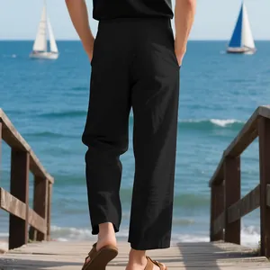 Detailed back view of men's loose black linen trousers worn on a scenic seaside pier