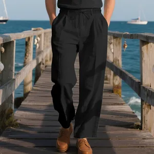 Detail view of men's loose black linen trousers on a scenic coastal pier background.