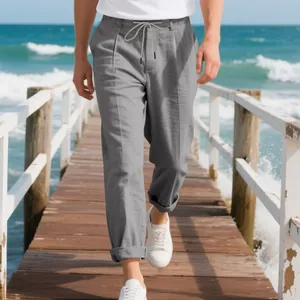Detailed look at men's loose gray linen straight-leg trousers on a summer pier