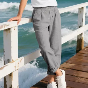 Relaxed men's grey linen trousers shown in a lifestyle seaside setting on a wooden pier