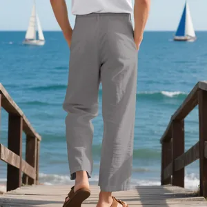 Breathable men's loose grey linen straight-leg pants shown from the back on a beach.