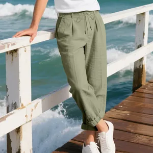Model wearing loose green linen trousers on a wooden pier by the sea
