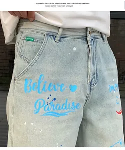 Close-up of graffiti print and paint splatter detail on light blue men's jeans
