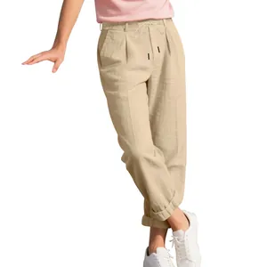 Close-up of loose beige men's linen trousers with drawstring waist and front pleats.