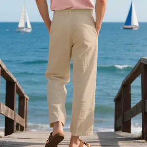 Detailed back view of men's loose straight-leg linen trousers on a scenic beach boardwalk
