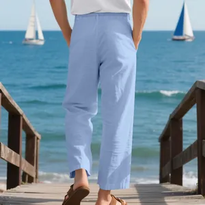 Back view of men's loose light blue linen trousers on a scenic beach boardwalk