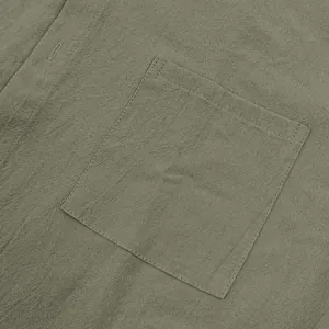 Primer plano de camisa de lino verde oliva con detalle de bolsillo y textura