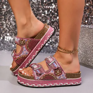 Close-up of pink platform sandals with rhinestone and pearl detailing on cork sole.