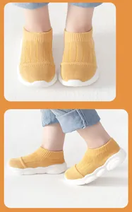Yellow toddler knit sock shoes with white non-slip soles shown in front and side views.
