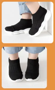 Close-up detail view of black baby sock shoes with flexible white soles for toddlers