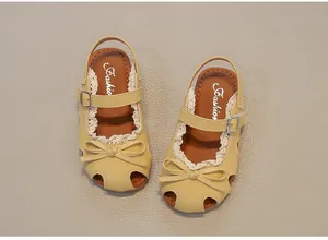 Detailansicht gelber Kinder-Sandalen mit schöner Schleife und Spitzenverzierung