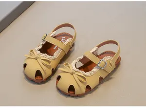 Detailansicht gelber geschlossener Mädchensandalen mit niedlicher Schleife und Spitze