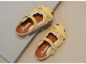 Detaillierte Draufsicht auf gelbe Kindersandalen mit süßen Schleifen und Spitze