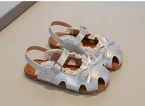 Nahaufnahme von silbernen Prinzessinnen-Sandalen für Mädchen mit Schleife und Spitze