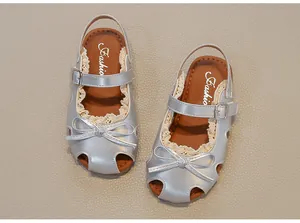 Detailansicht der silbernen Mädchensandalen mit Schleife und zarter Spitze.