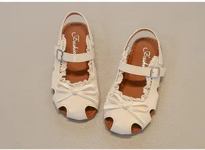 Draufsicht auf elegante beige Kinder-Sandalen mit Schleife und Spitzenbesatz