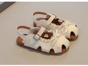 Detailansicht der weißen geschlossenen Mädchensandalen mit eleganter Schleife und Spitze