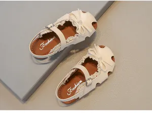 Elegante weiße geschlossene Mädchensandalen mit feinem Spitzenbesatz und Schleifenakzent.