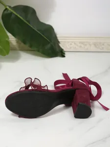 Detailed view of burgundy suede block heel sandals with ribbon ties and ruffle mesh strap