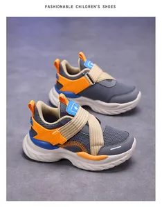 Detalle de zapatillas de malla transpirable para niños con suela blanda en gris y naranja.