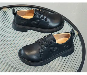 Black leather girl shoes with heart pattern on a textured glass table
