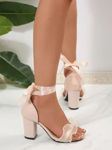 Elegant nude block heel sandals with ankle ribbons and ruffled front strap
