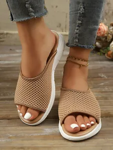 Détail de sandales plates en maille respirante kaki pour femmes sur fond de bois rustique