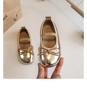 Detail of gold metallic girl's princess flat shoes with bow and elastic strap