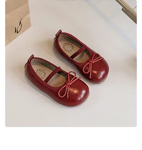 Detailed close-up of girls' red Mary Jane leather shoes featuring a bow and soft sole