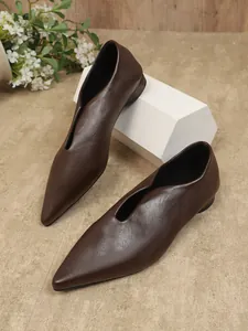 Gedetailleerd overzicht van elegante bruine puntige ballerina's met V-hals op wit blok