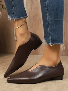 Close-up van bruine leren platte schoenen met spitse neus en V-snit voor een retro look.
