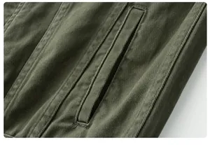 Macro view of olive green denim jacket showing welt pocket detail and fabric texture.