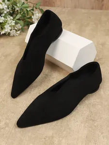 Detailweergave van zwarte suède ballerina's met puntige neus en V-halslijn