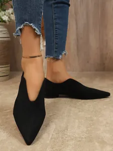 Detailopname van zwarte suède ballerina's met puntige neus gedragen met denim voor een chique look.