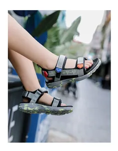Side view of boy wearing grey and black sports sandals with camouflage soles