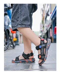 Macro detail shot of boys' black outdoor sandals featuring vibrant orange splatter soles