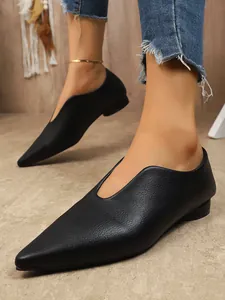 Detailopname van zwarte platte damesschoenen met puntige neus en vintage V-hals.