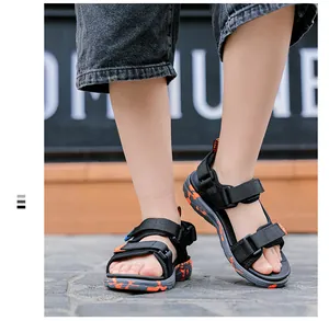 Macro view of black boy's sandals featuring vibrant orange camouflage soft soles