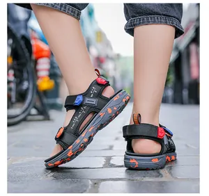 Close-up of boys' lightweight black sandals with colorful accents on a stone path