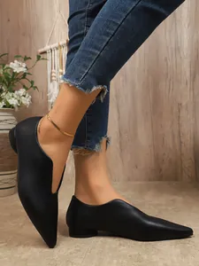 Elegante zwarte platte schoenen met spitse neus gedragen door model voor een look