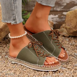 Gros plan sur des claquettes en toile vert olive à lacets avec détails de semelle tressée